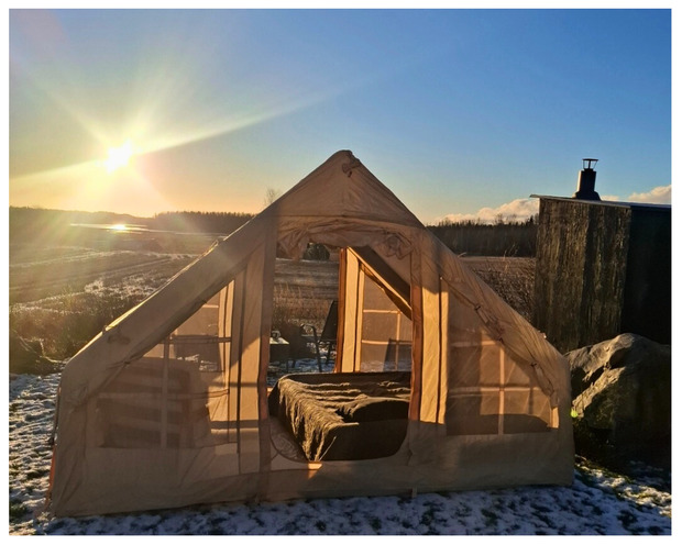 Glamping-teltta peltomaisemassa talvisessa auringonlaskussa, teltan sis&auml;ll&auml; n&auml;kyviss&auml; paris&auml;nky.
