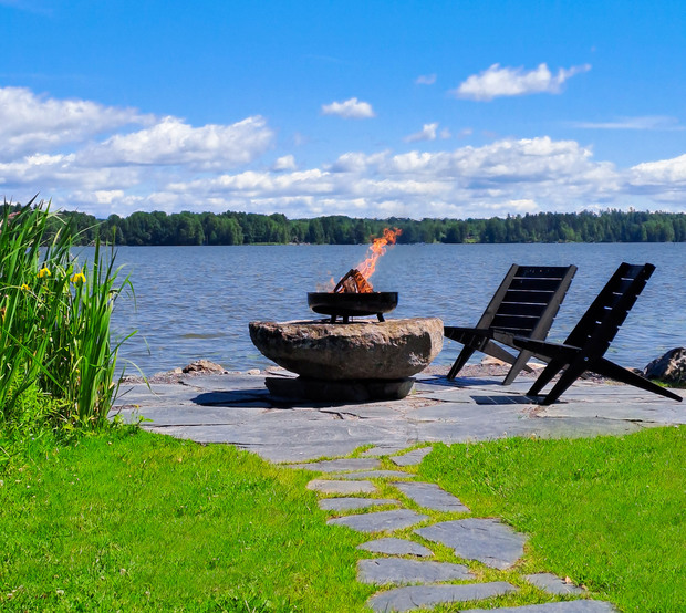 Palava nuotio kivellä järven rannassa ja kaksi tuolia